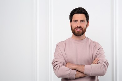 Portrait of handsome man near white wall, space for text