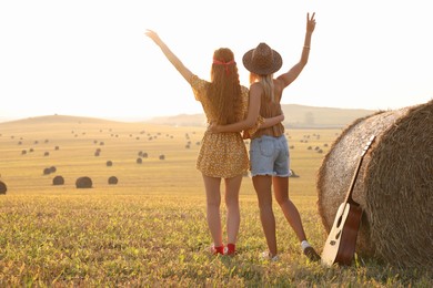 Hippie women near hay bale in field, back view