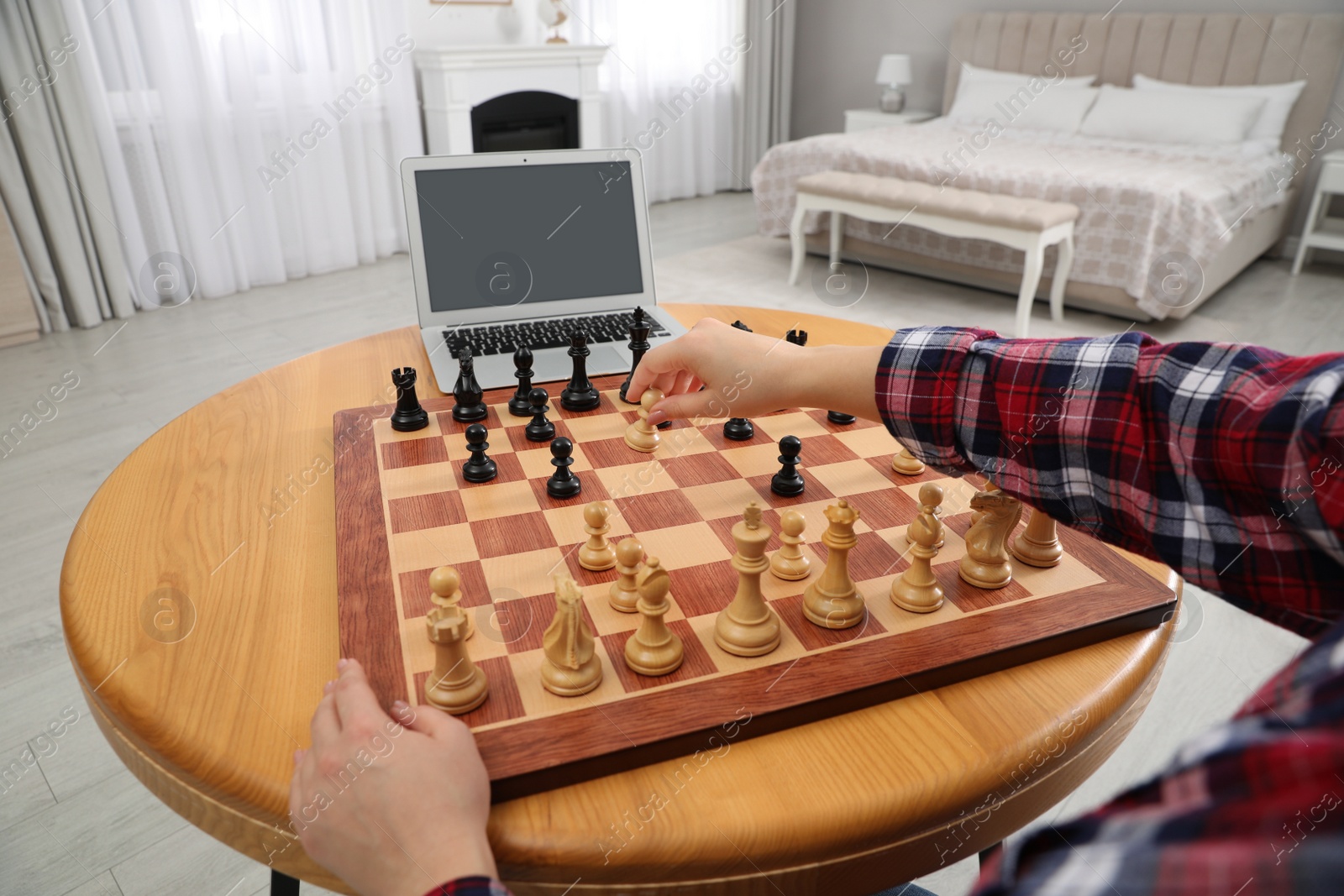 Photo of Woman playing chess with partner through online video chat at table indoors, closeup