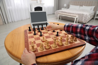 Woman playing chess with partner through online video chat at table indoors, closeup