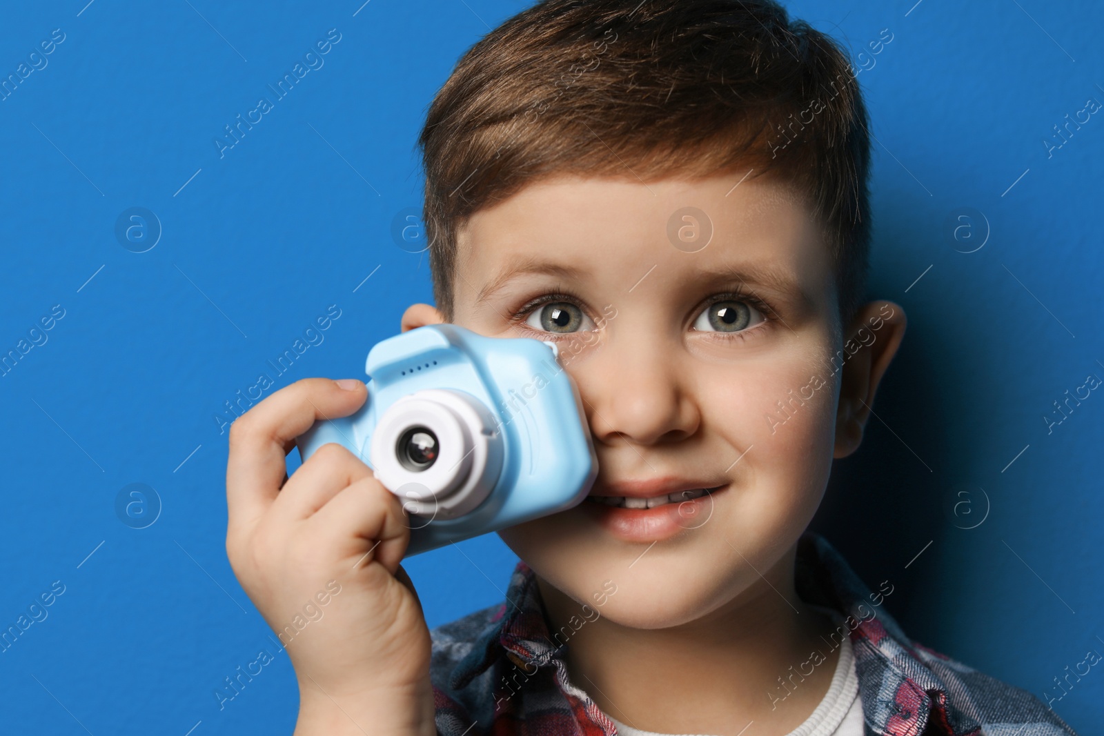 Photo of Little photographer with toy camera on blue background