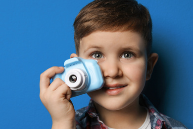 Photo of Little photographer with toy camera on blue background