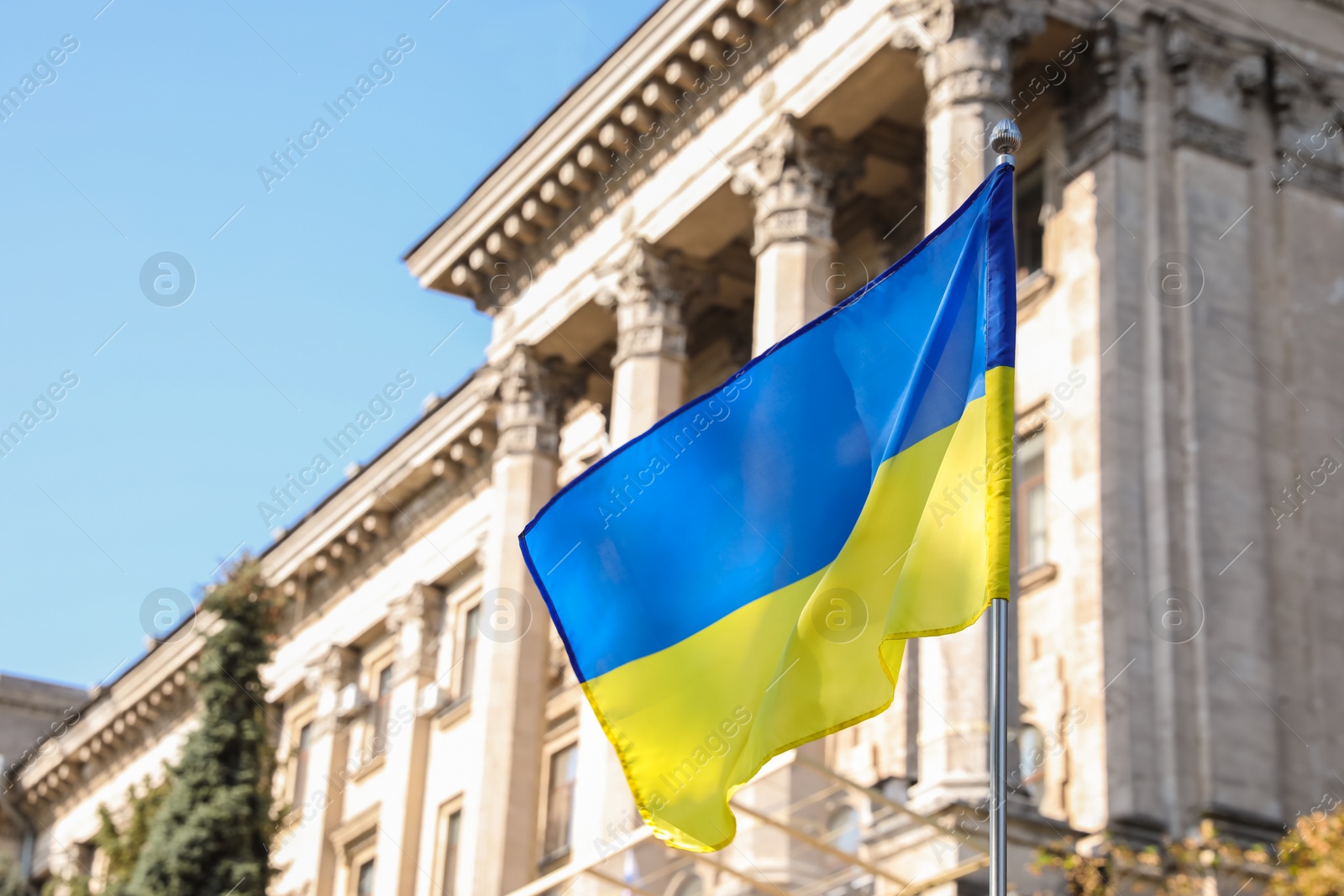 Photo of National flag of Ukraine fluttering near building on sunny day