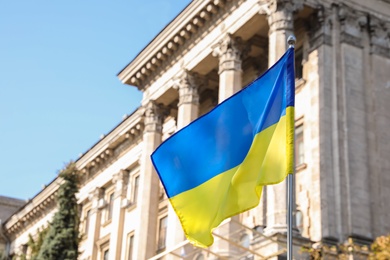 Photo of National flag of Ukraine fluttering near building on sunny day