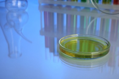 Photo of Petri dish with yellow liquid on white table, space for text