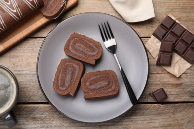 Photo of Tasty chocolate cake roll with cream on wooden table, flat lay