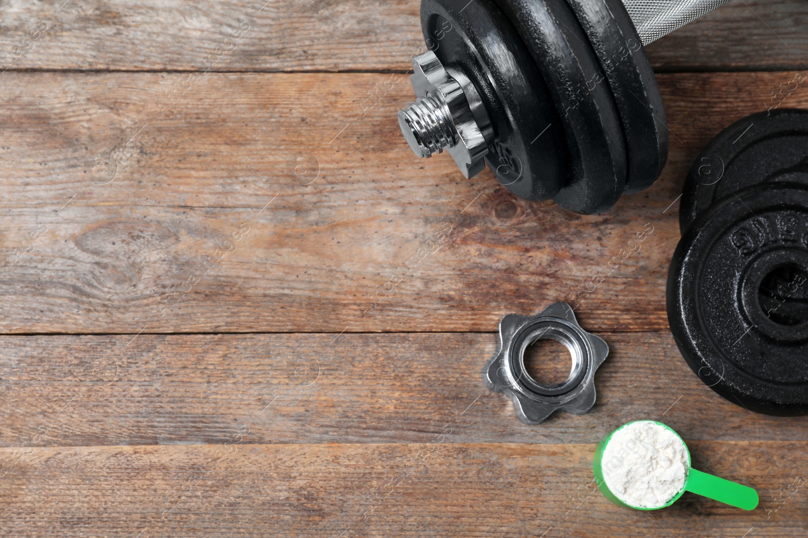 Photo of Flat lay composition with protein powder and dumbbell on wooden background. Space for text