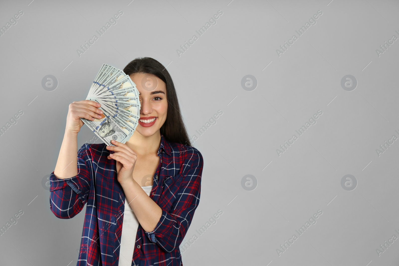 Photo of Young woman with money on light grey background. Space for text