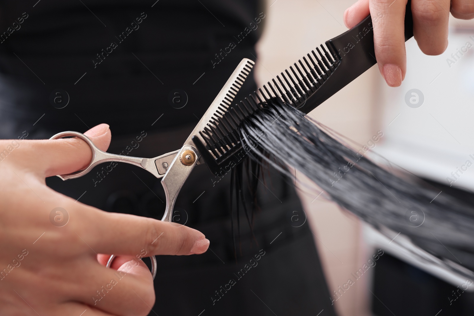 Photo of Professional hairdresser cutting woman's hair in beauty salon, closeup