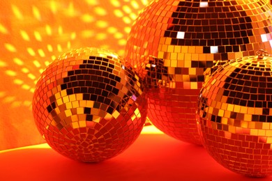 Photo of Many shiny disco balls near color wall, toned in orange