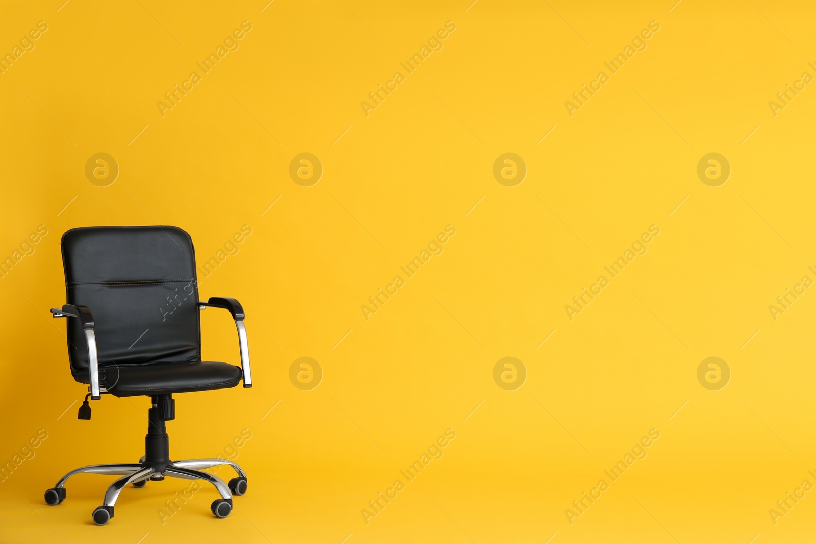 Photo of Modern office chair on yellow background. Space for text