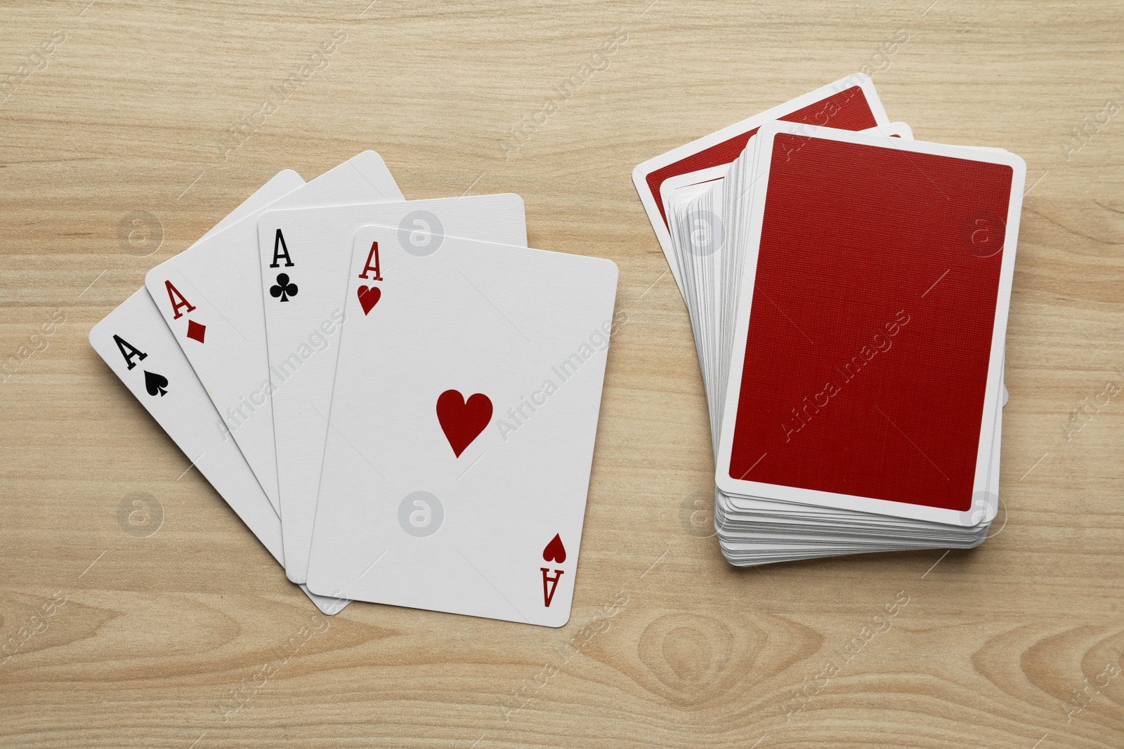 Photo of Four aces and deck of playing cards on wooden table, flat lay