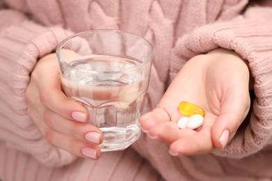 Woman with glass of water and pills, closeup view