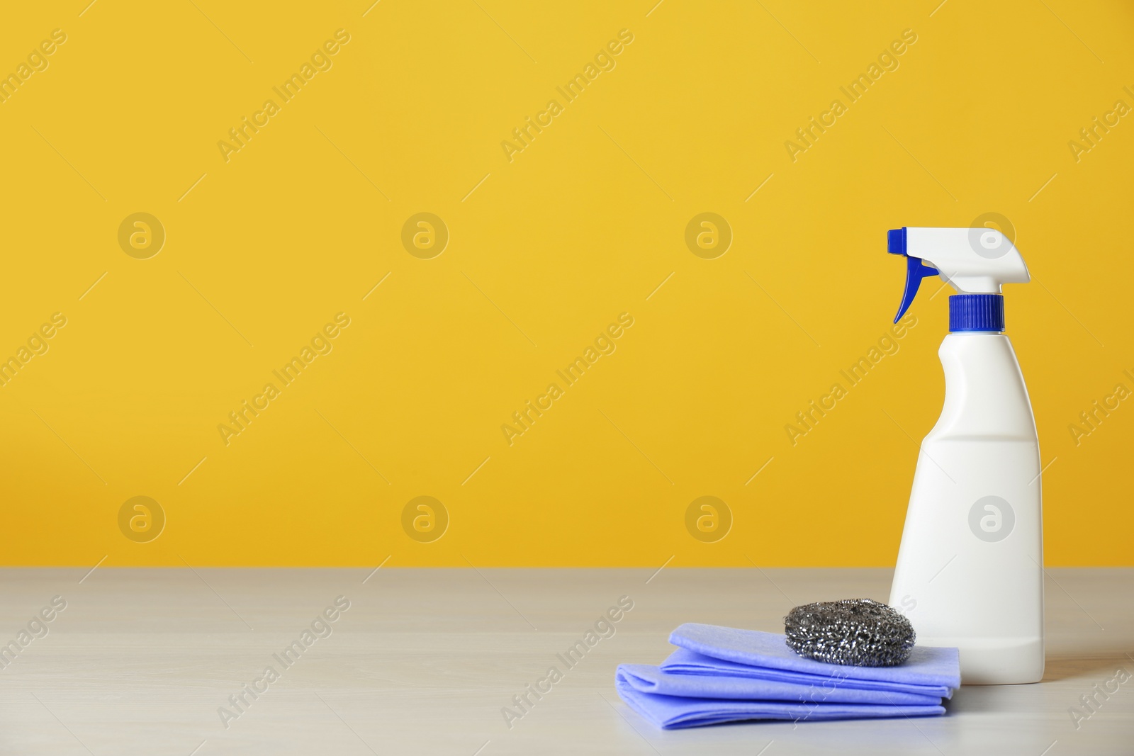 Photo of Bottle of cleaning product and supplies on light table. Space for text