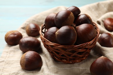 Photo of Wicker bowl with roasted edible sweet chestnuts on table, closeup