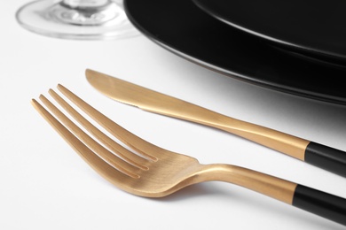Photo of Beautiful setting with gold cutlery on white table, closeup