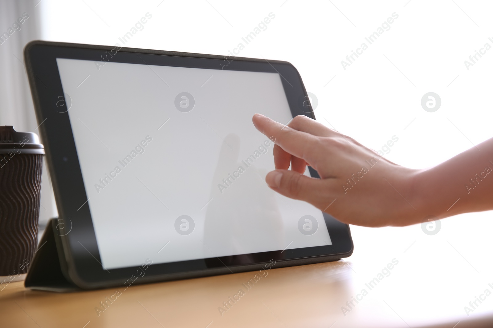 Photo of Woman working with modern tablet at wooden table, closeup. Space for design