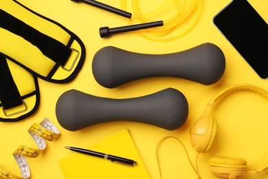 Photo of Flat lay composition with dumbbells on yellow background