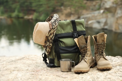 Set of camping equipment on rock near lake