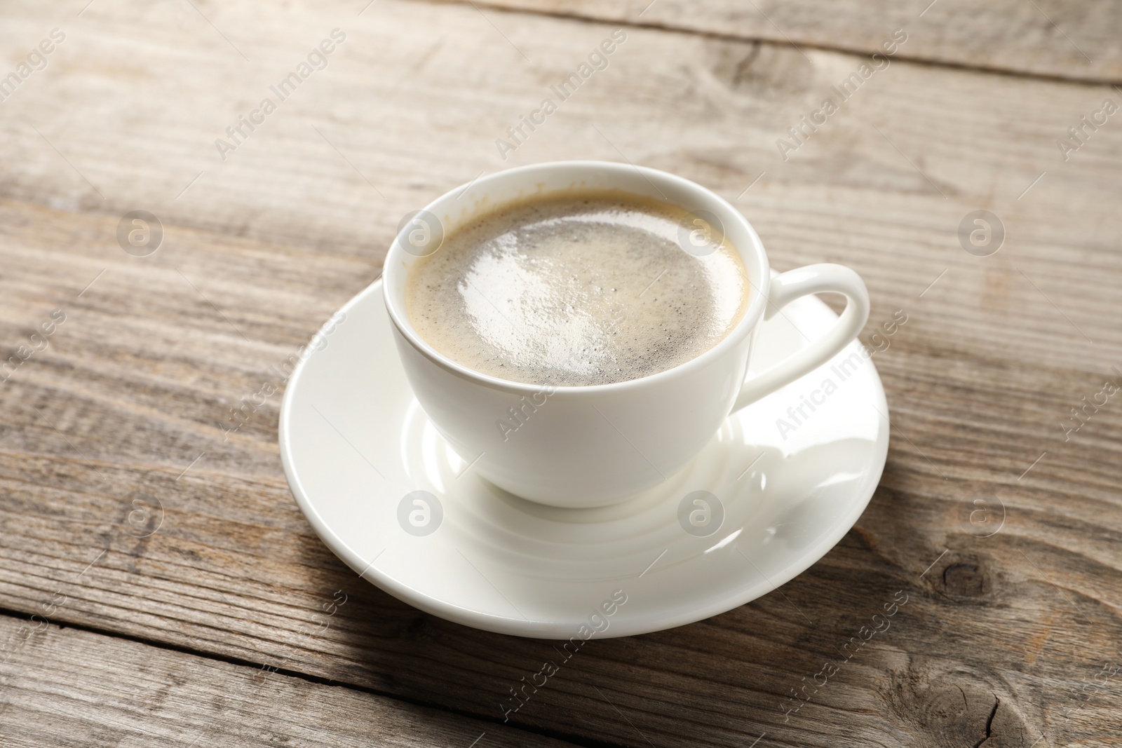 Photo of Tasty coffee in cup on wooden table, closeup