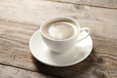 Tasty coffee in cup on wooden table, closeup