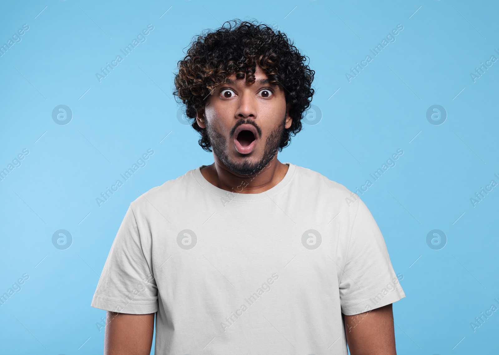 Photo of Handsome surprised man on light blue background