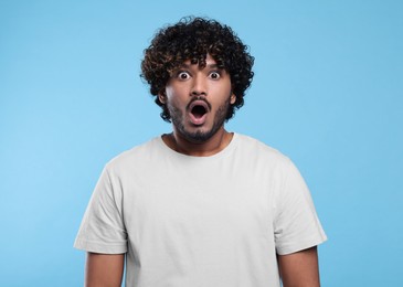 Handsome surprised man on light blue background