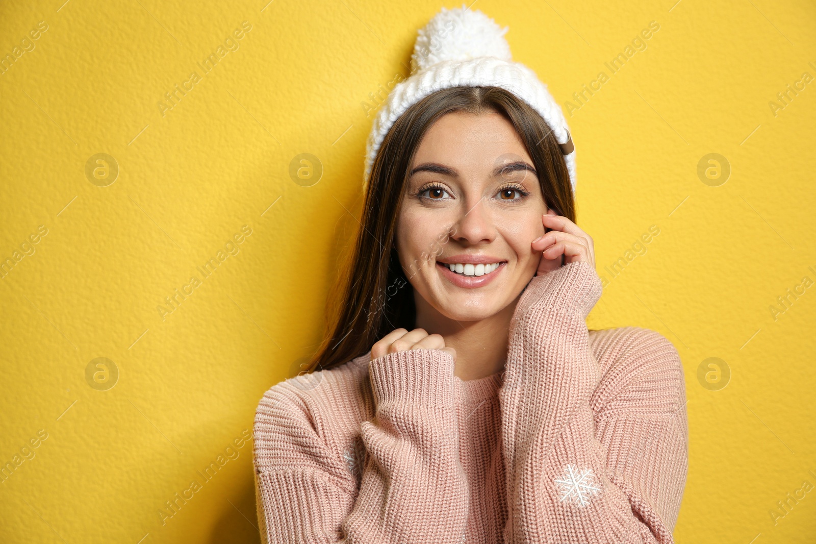 Photo of Beautiful young woman in warm sweater with hat on color background. Space for text