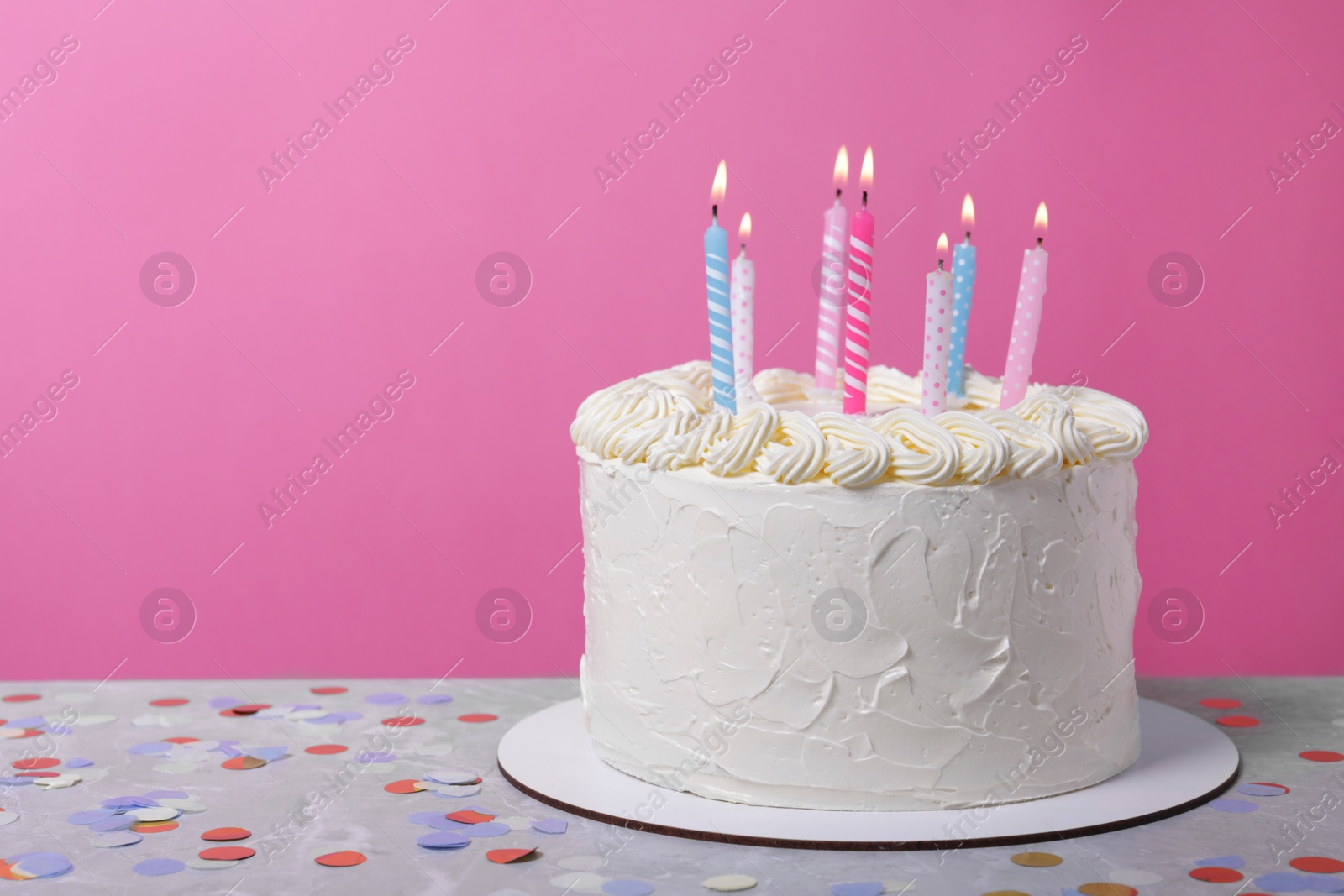 Photo of Delicious cake with cream and burning candles on grey table. Space for text
