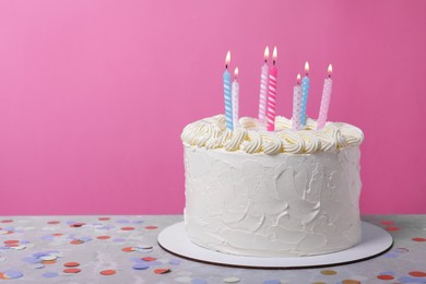 Photo of Delicious cake with cream and burning candles on grey table. Space for text