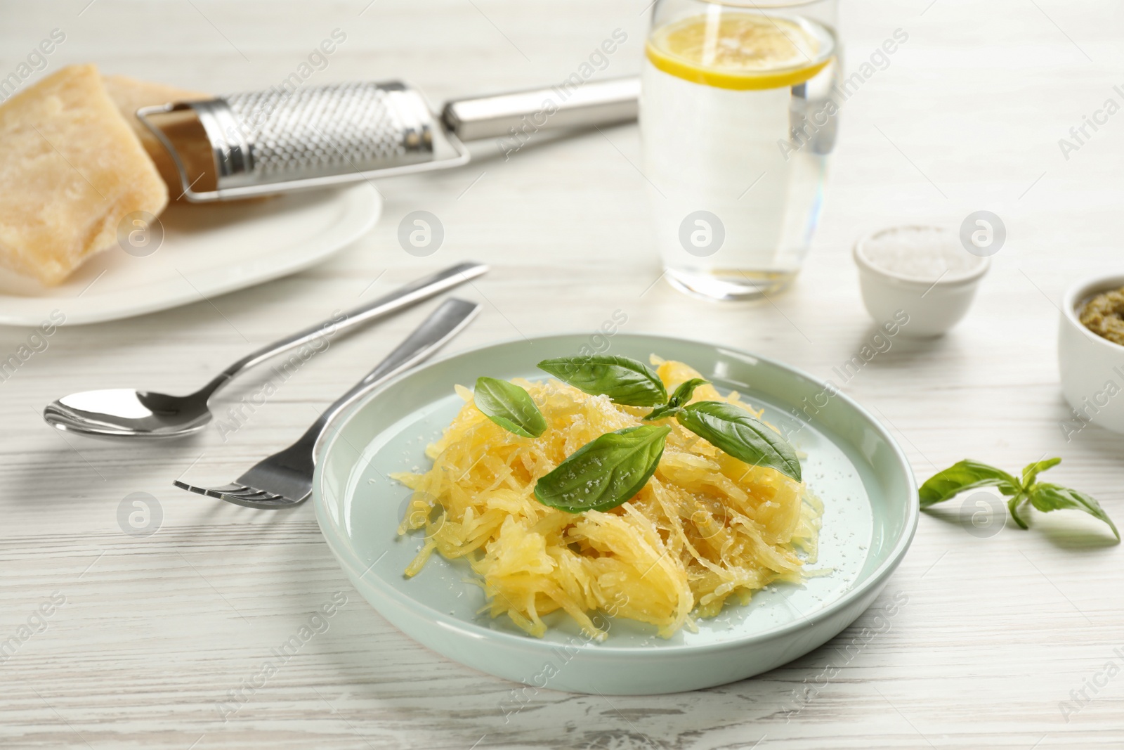 Photo of Tasty spaghetti squash with basil and cheese served on white wooden table