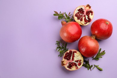 Flat lay composition with ripe pomegranates on violet background. Space for text