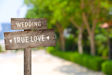 Image of Wooden plaques with inscriptions Wedding and True Love outdoors, space for text 