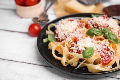 Photo of Delicious pasta with tomato sauce, basil and parmesan cheese on white wooden table, closeup. Space for text