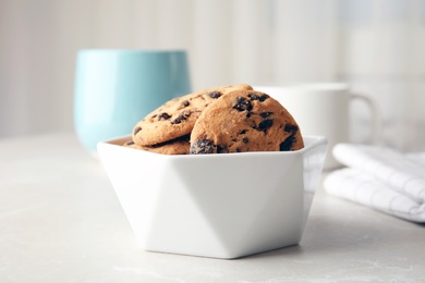 Photo of Bowl with tasty chocolate chip cookies on table