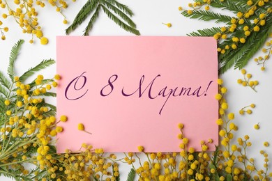 Image of Beautiful mimosa flowers and greeting card with text 8 March written in Russian  on white background, flat lay 