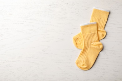 Photo of Cute child socks on white wooden background, top view. Space for text