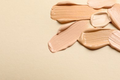 Samples of skin foundation on beige background, closeup. Space for text