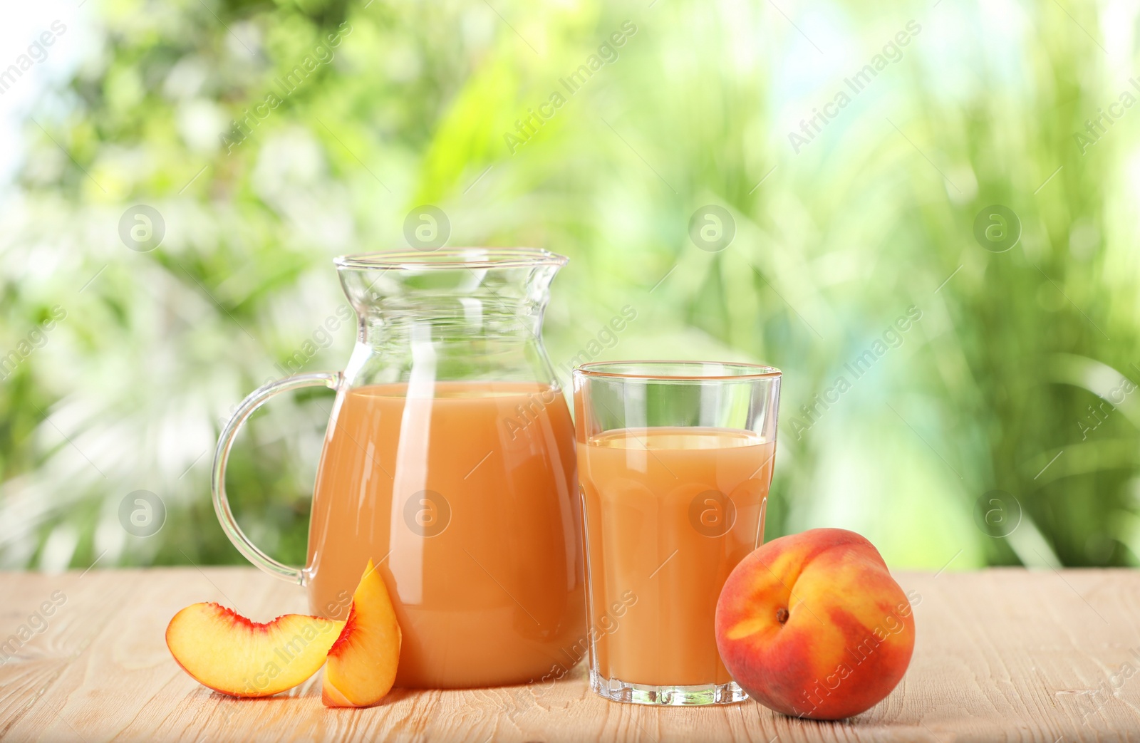 Photo of Tasty peach juice and fresh fruits on wooden table outdoors