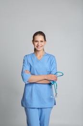 Portrait of young medical assistant with stethoscope on color background