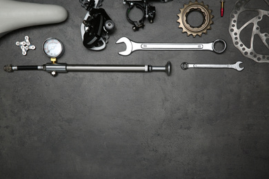 Photo of Set of different bicycle tools and parts on grey stone table, flat lay. Space for text