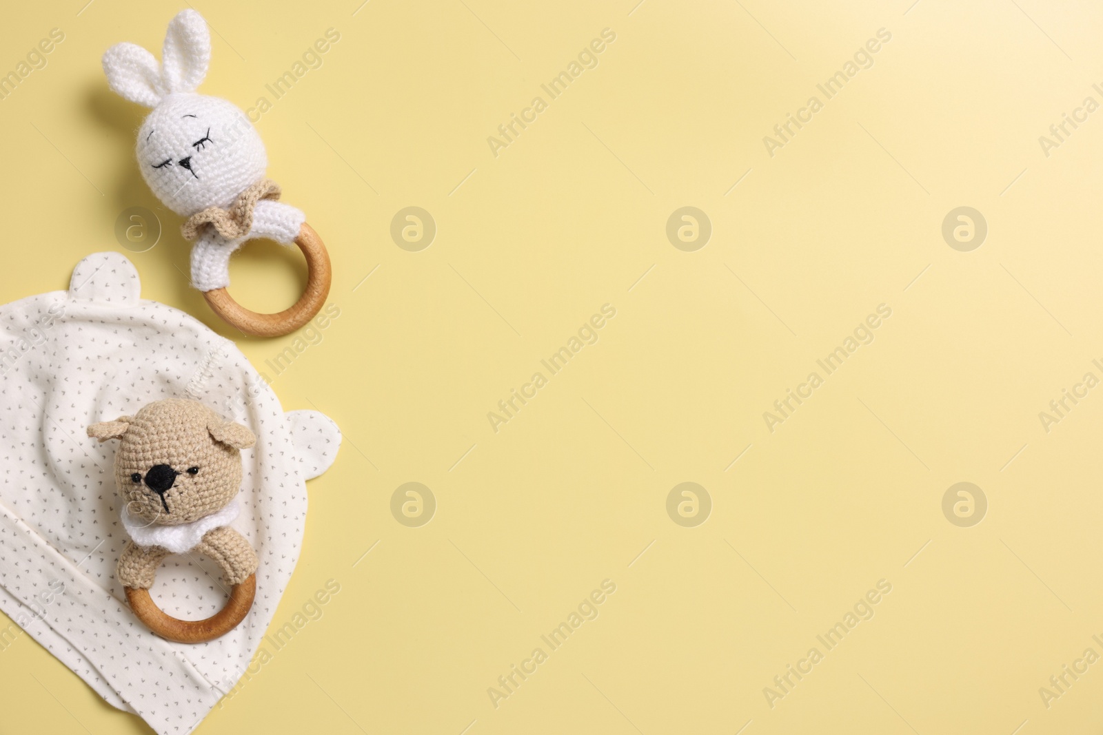 Photo of Baby accessory. Rattles and hat on yellow background, top view. Space for text