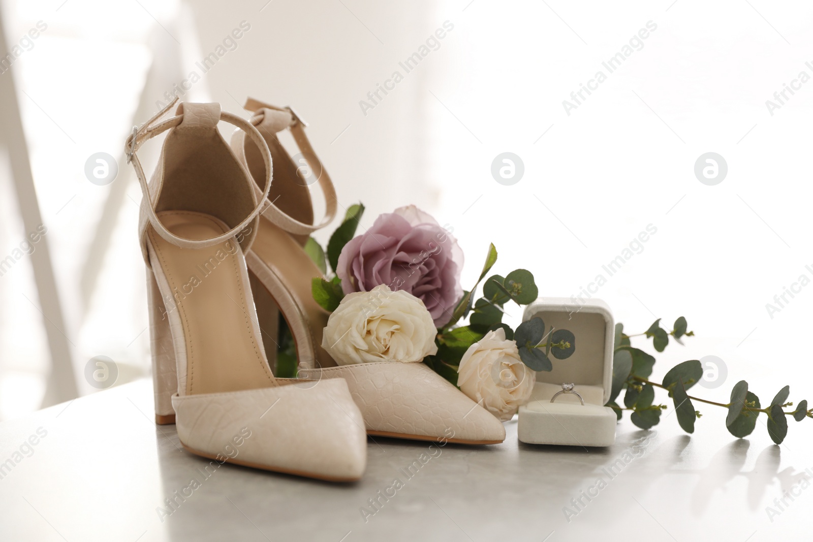 Photo of Composition with engagement ring and wedding shoes on light grey table, closeup. Bride dressing