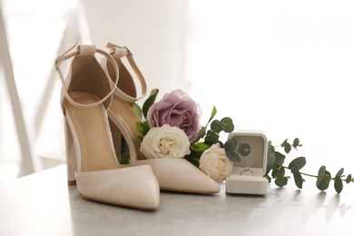 Photo of Composition with engagement ring and wedding shoes on light grey table, closeup. Bride dressing