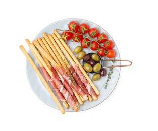 Photo of Plate of delicious grissini sticks with prosciutto, tomatoes and olives on white background, top view
