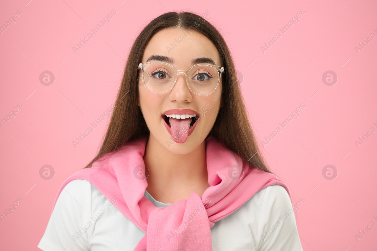 Photo of Happy woman showing her tongue on pink background