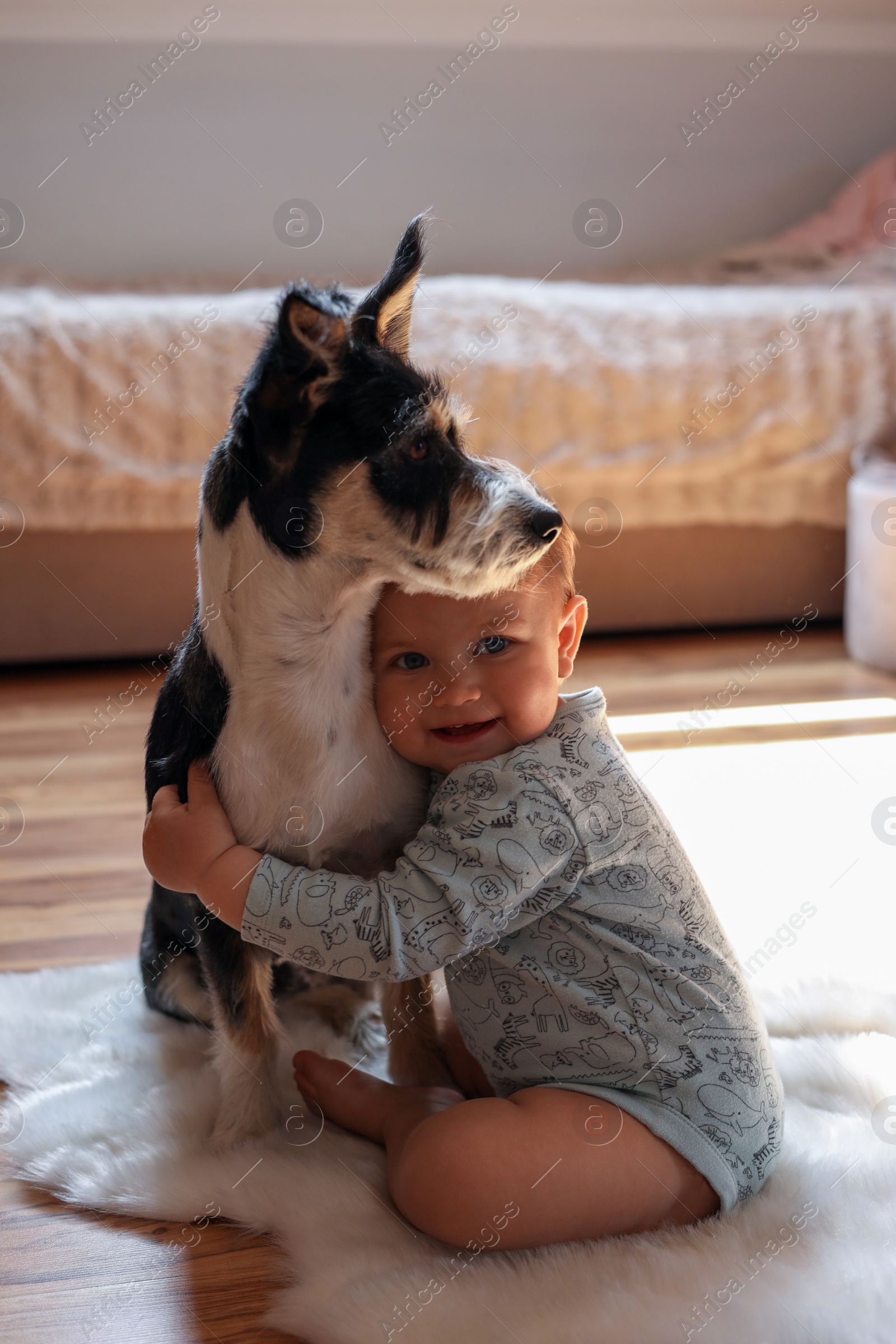 Photo of Adorable baby and cute dog on faux fur rug at home