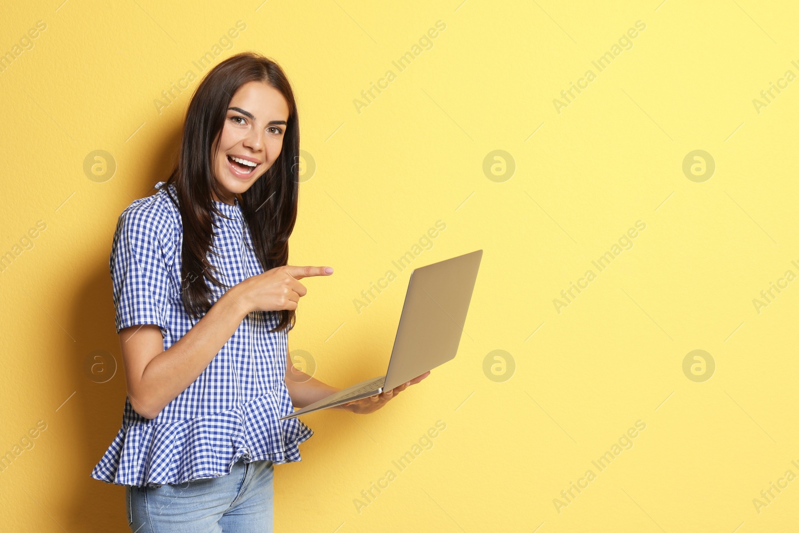 Photo of Young woman with modern laptop on color background