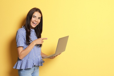 Young woman with modern laptop on color background