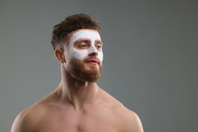 Handsome man with facial mask on his face against grey background, space for text